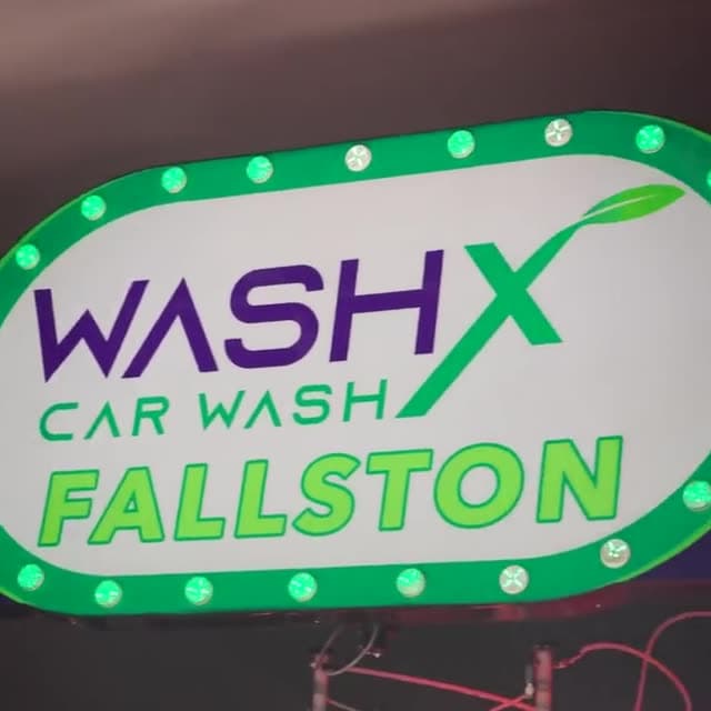 The lit WashX Car Wash Fallston sign over the tunnel entrance