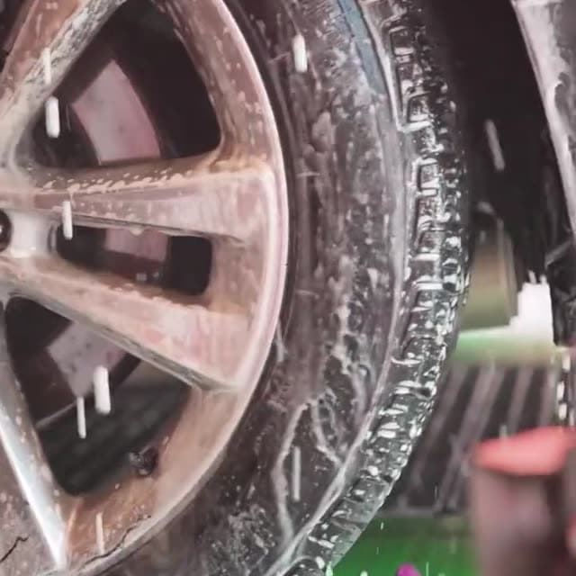 Foam and water spraying over a tire in the wash tunnel