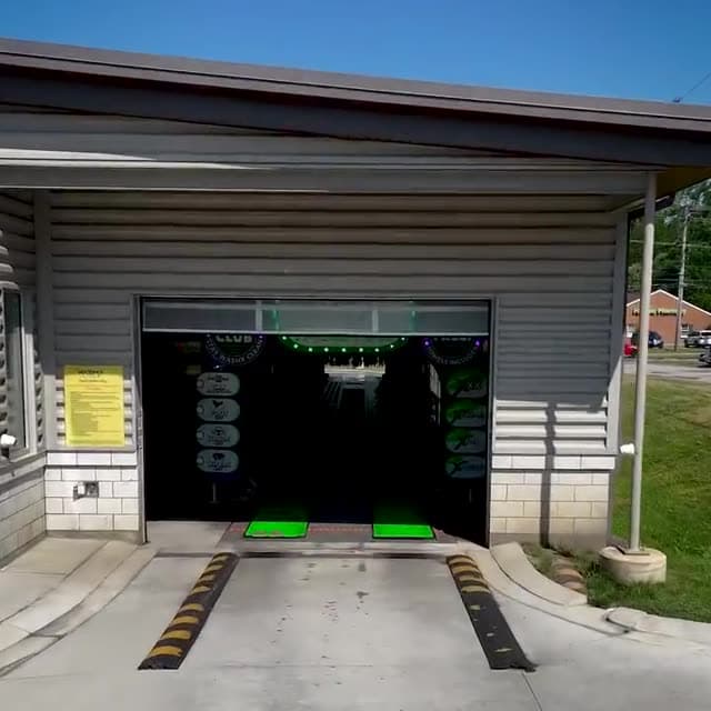 The entrance to the WashX wash tunnel, lit green inside