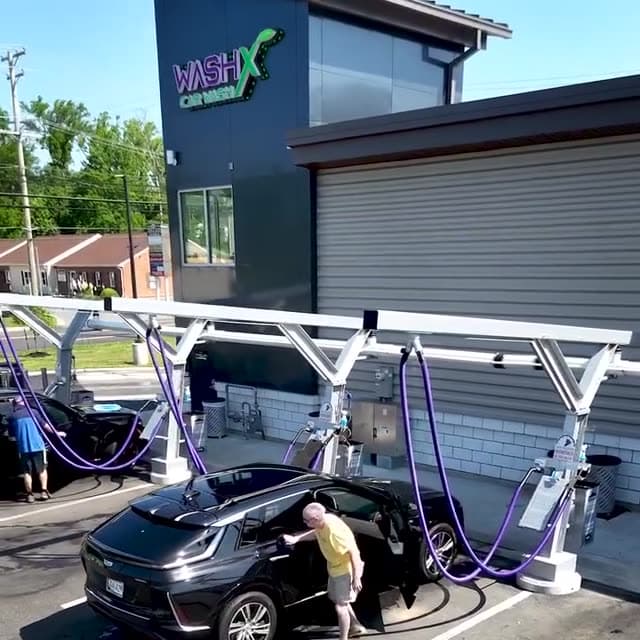 A driver cleaning their car at the vacuum stations beside the WashX building